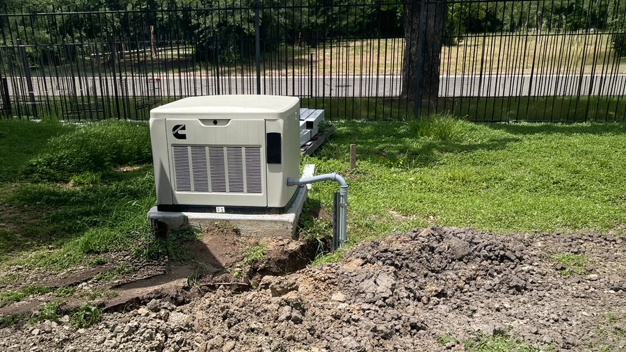 A Cummins standby generator newly set on its pad in a backyard