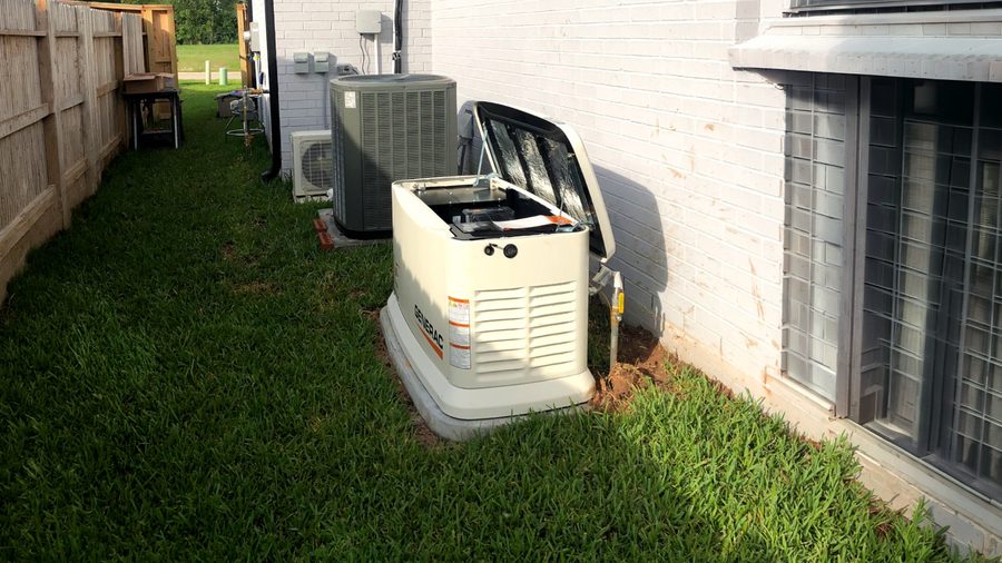 A standby generator installed in a side yard next to air conditioning units