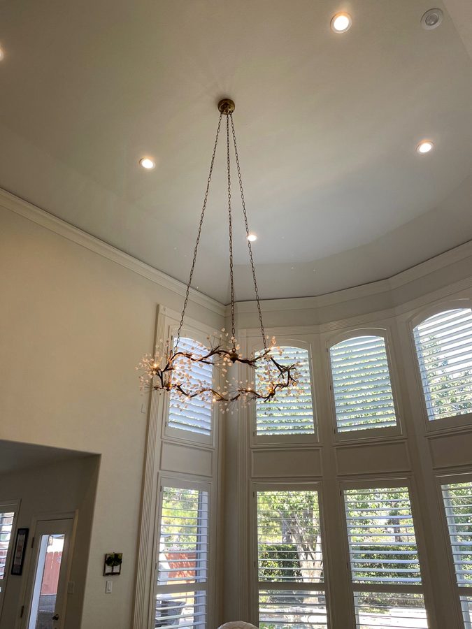 An open ring chandelier hung high in a room with tall windows