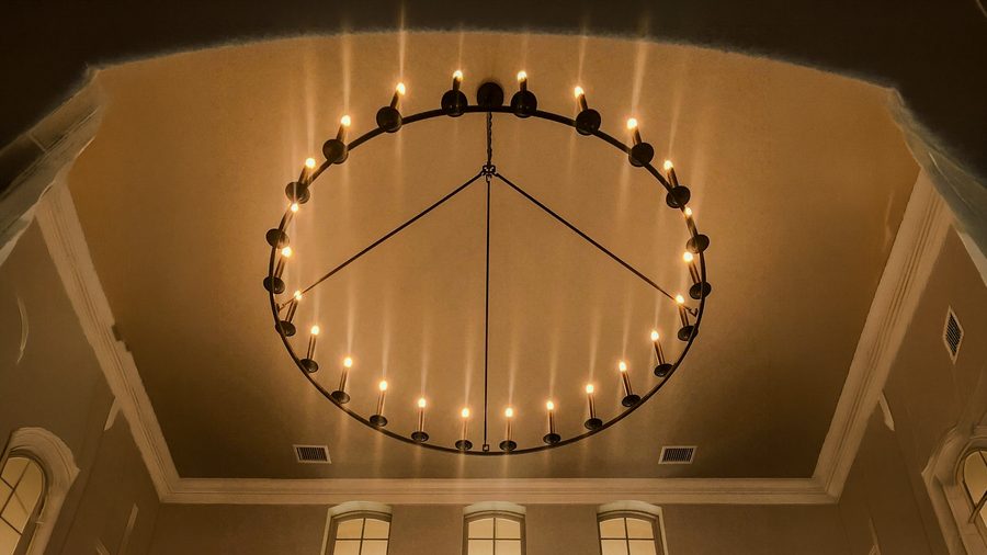 A large ring chandelier with candle-style lamps in a coffered ceiling