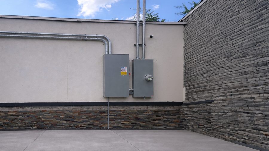 Two service enclosures with conduit runs on a stucco wall